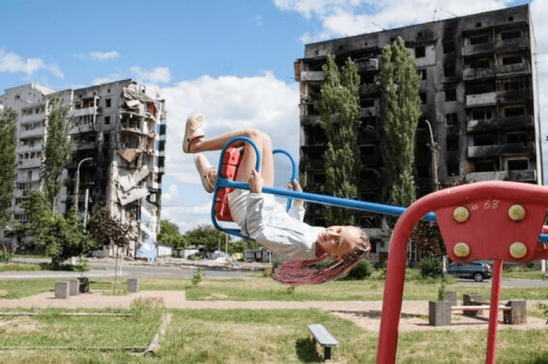A girl on a swing near the destroyed building in Borodianka.