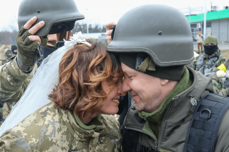 Lesia Ivashchenko and Valeriy Fylymonov, both members of the Ukrainian Territorial Defense Forces, listen to a priest during their wedding at a checkpoint in Kyiv on March 6.